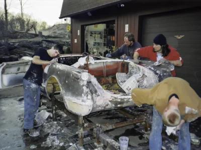Technicians working on 1954 Corvette bare fiberglass body on rotisserie at Corvette Connection