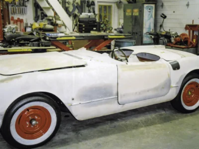 1954 Corvette body in white with red wheels and whitewall tires during assembly at Corvette Connection