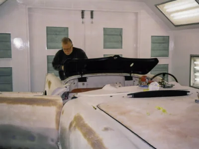 Technician fitting 1954 Corvette body panel in paint booth at Corvette Connection