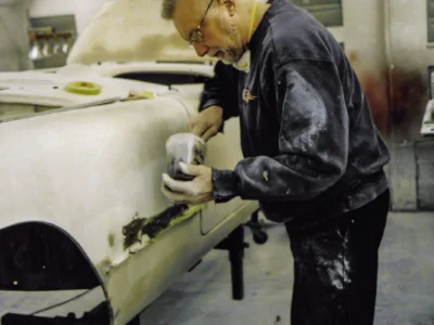 Technician block sanding 1954 Corvette body in primer at Corvette Connection