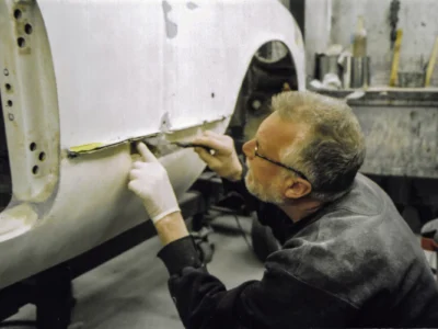 Technician hand-finishing fiberglass body work on 1954 Corvette at Corvette Connection