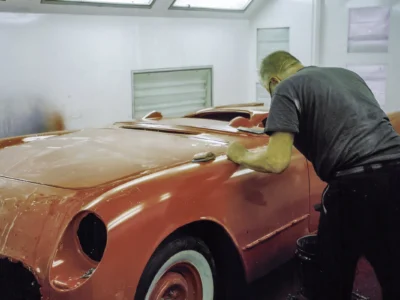 Technician polishing 1954 Corvette rear fender in red paint at Corvette Connection