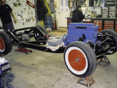 Technician working on 1954 Corvette Blue Flame engine on rolling chassis at Corvette Connection