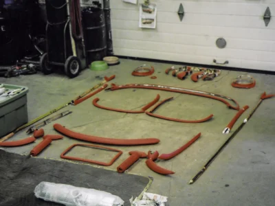 1954 Corvette freshly painted red frame rails and brackets laid out on shop floor