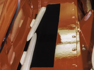 1954 Corvette door sill and kick panel in red paint with black carpet during interior assembly