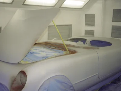 1954 Corvette body masked with yellow tape for final white paint in paint booth at Corvette Connection