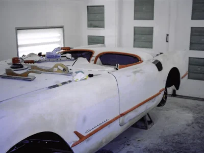 1954 Corvette body in white paint with red interior visible during final assembly