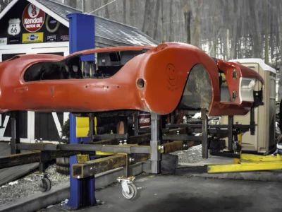 1957 Corvette red body on lift with fenders removed during teardown at Corvette Connection