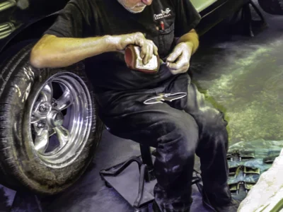 Technician polishing 1957 Corvette wheel well area after black paint at Corvette Connection