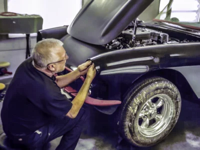 Technician hand sanding 1957 Corvette front fender after black base coat at Corvette Connection