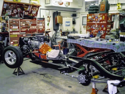 1957 Corvette chassis and drivetrain in shop with body components and parts at Corvette Connection