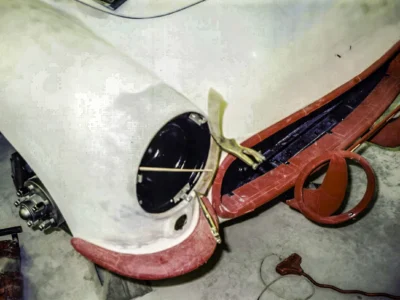 Headlight bucket area close-up on 1957 Corvette showing primer and red original paint