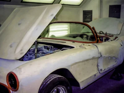 1957 Corvette body in primer and red showing open hood and fender fitment at Corvette Connection
