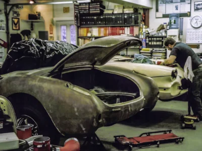 1957 Corvette in primer with hood up showing engine bay in shop at Corvette Connection
