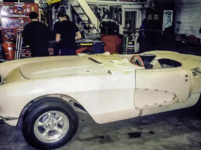 1957 Corvette body in primer on rolling chassis showing panel fitment at Corvette Connection