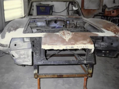 1965 Corvette hood panel on stand showing bare fiberglass during body work