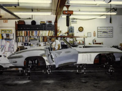 1965 Corvette body in primer on rolling chassis in shop during assembly