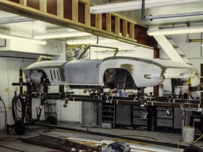 1965 Corvette body in primer on rotisserie in shop during panel fitting