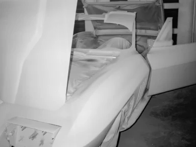 1965 Corvette Sting Ray body in white primer showing hood and fender in paint booth