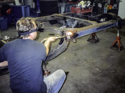 Technician working on bare frame of 1966 Corvette Sting Ray during teardown
