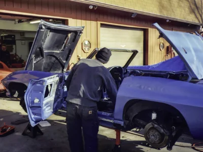 Technician inspecting 1966 Corvette Sting Ray body with door open at Corvette Connection