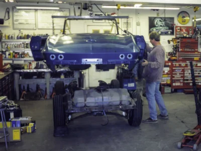 Technician working on rear of 1966 Corvette body during disassembly at Corvette Connection