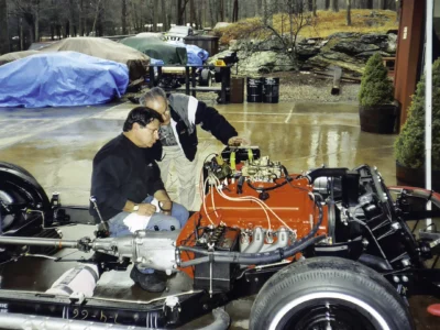 Technician working on red engine in 1966 Corvette rolling chassis at Corvette Connection