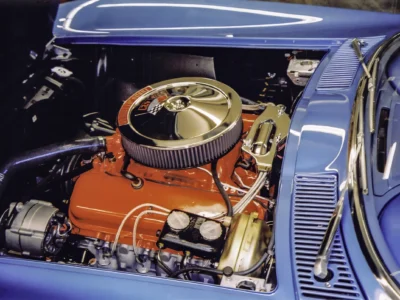Restored red engine with gold air cleaner in 1966 Corvette Sting Ray engine bay at car show
