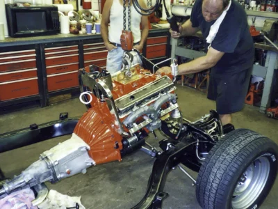 Technicians guiding the engine and transmission into the 1968 Corvette chassis