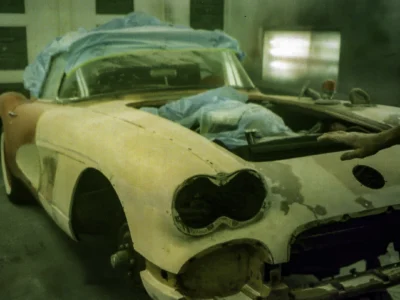 Bare 1958 Corvette body shell stripped to fiberglass with hood up during teardown at Corvette Connection