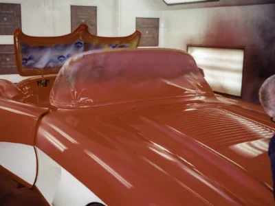 Side view of red and white 1958 Corvette body during chrome trim reinstallation