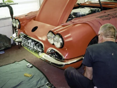 Front quarter of red 1958 Corvette with hood up during engine reinstallation