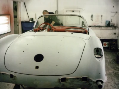 Front view of 1958 Corvette body in white primer with empty headlight bezels at Corvette Connection