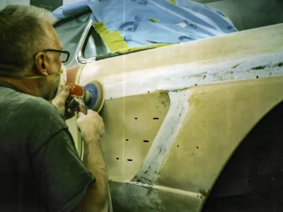 Corvette Connection technician sanding 1958 Corvette body in primer during bodywork stage