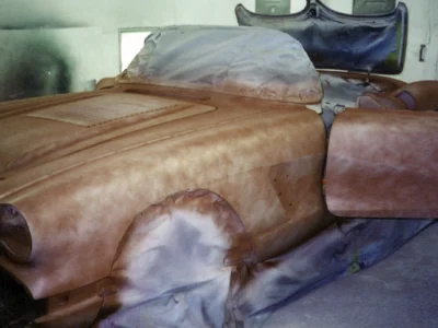Hood and front fender detail of 1958 Corvette in red primer during bodywork stage