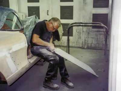 Corvette Connection technician kneeling beside 1958 Corvette during paint prep