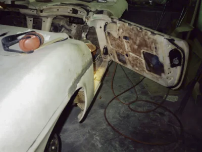 Corvette Connection technician with dust mask sanding 1962 Corvette front fender