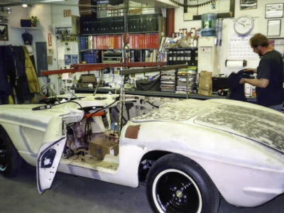Side profile of 1962 Corvette body in primer mounted on rolling chassis at Corvette Connection