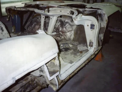 1962 Corvette body shell on tall stands with frame removed underneath at Corvette Connection