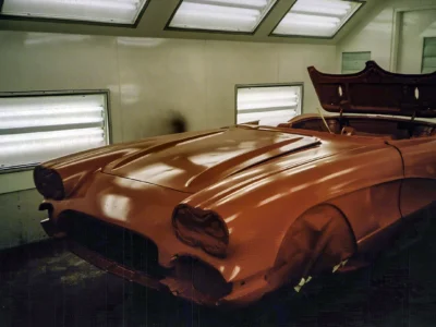 Front three-quarter of 1962 Corvette body in red base coat inside paint booth