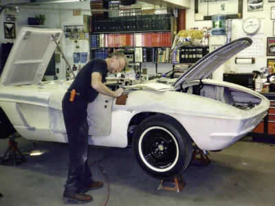 Corvette Connection technician working on 1962 Corvette body in primer mounted on chassis