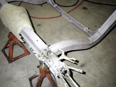 Bare 1962 Corvette frame suspended on chains during frame restoration at Corvette Connection