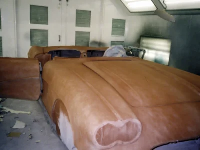 Front three-quarter of 1962 Corvette body in fresh red paint inside paint booth