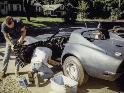 Person washing completed 1968 Corvette Stingray in black at Corvette Connection