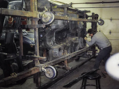 Technician removing fiberglass body panels from 1968 Corvette Stingray during teardown