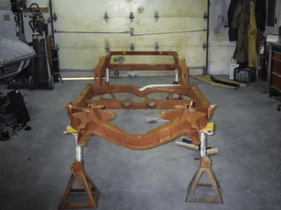 1968 Corvette bare frame on jack stands showing orange primer at Corvette Connection