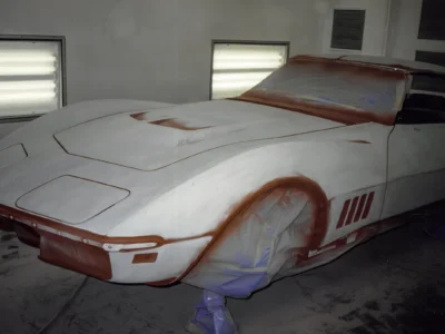 1968 Corvette Stingray body in primer with blue masking tape in paint booth
