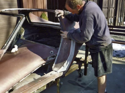 Technician repairing or fitting a Corvette body panel during restoration
