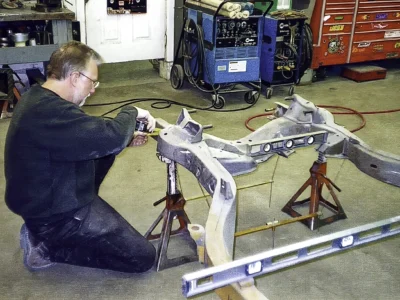 Technician working on a stripped 1968 Corvette frame section