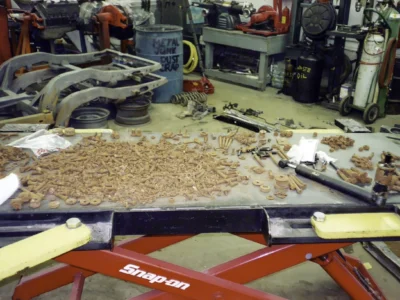 Corvette body and restoration parts staged near a lift inside the shop